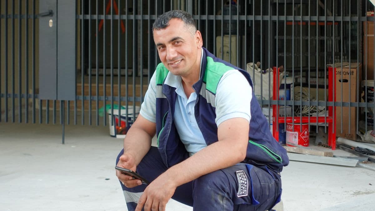 Trabajador de construcción sonriendo con su celular en obra